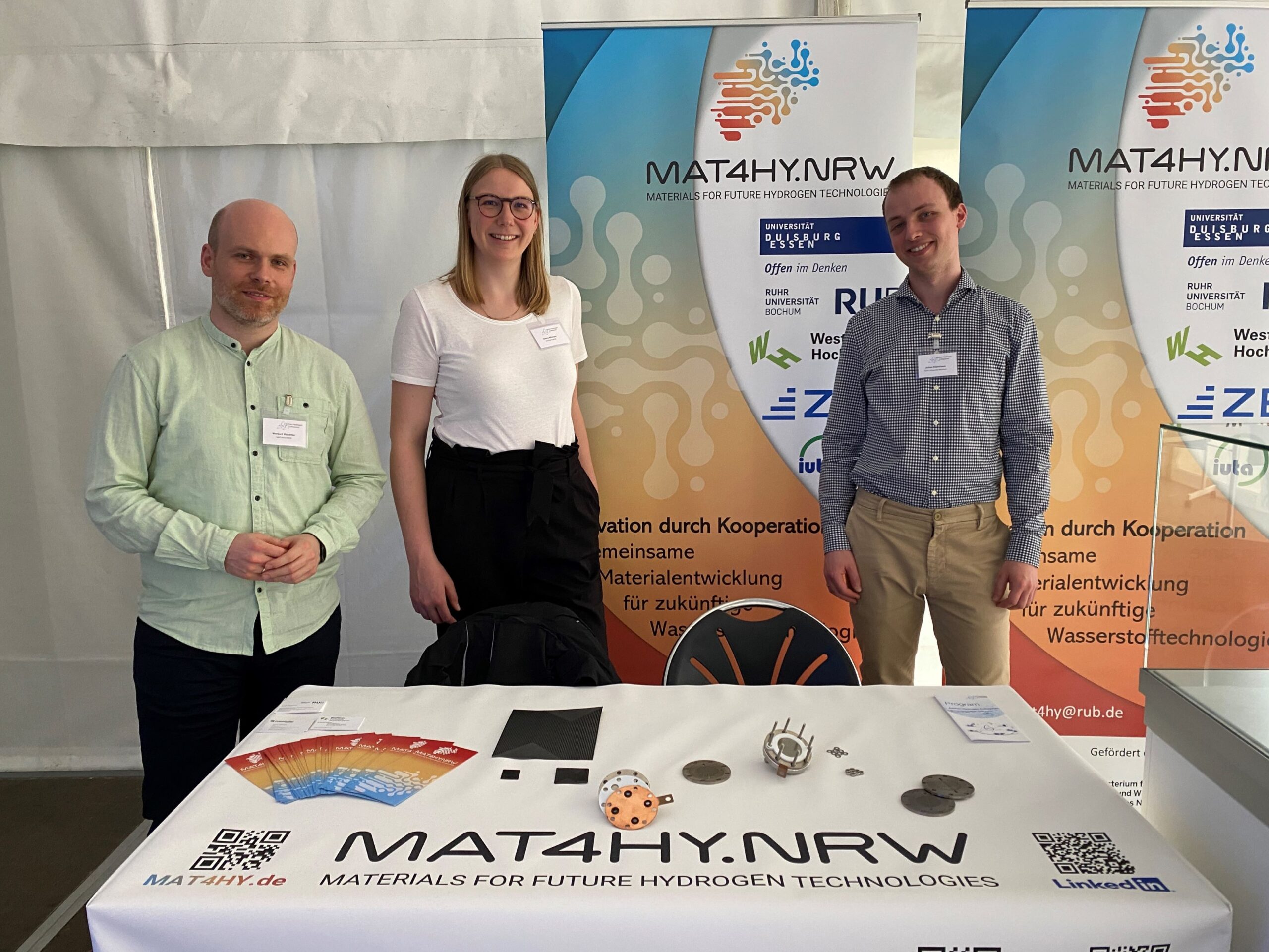Norbert Kazamer, Janna Wierper und Julian Kleinhaus am MAT4HY.NRW-Stand auf dem Aachen Hydrogen Colloquium 2024.